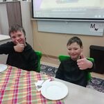 Dwóch chłopców siedzi przy stole i pokazuje kciuk.