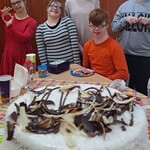 Tort. Za tortem świętujący uczniowie urodziny Mateusza.
