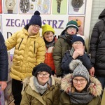 Grupa uczniów na tle witryny pracowni zegarmistrzowskiej.