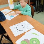 Uczeń siedzi przy ławce. Na ławce rozłożone ma obrazki ze zdrową i niezdrową żywnością, dopasowuje obrazek z gruszką do zdrowej żywności.