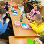 Uczniowie siedzą przy ławkach i spożywają wspólne śniadanie.