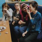 5 uczniów siedzi na kanapie. Przed nimi stoi stół na którym znajdują się przekąski -popcorn i chipsy.