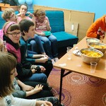 Uczniowie siedzą na kanapach  i czekają na rozpoczęcie seansu.