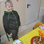 Uśmiechnięty uczeń stoi przed swoim urodzinowym stołem.