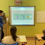 Uczniowie patrzą na slajd na ekranie tablicy multimedialnej.