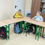 Uczniowie siedzą przy ławkach i degustują pizzę.