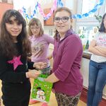 Dziewczyna częstuje cukierkami grupę uśmiechniętych uczniów.