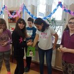 Dziewczyna częstuje cukierkami grupę uśmiechniętych uczniów.