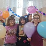 Grupa uczniówi z kolorowymi balonami pozuje do zdjęcia.