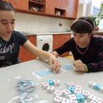 Dwie dziewczyny układają klocki- okna na rysunkach domów.