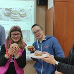 Nauczycielka częstuje grupę uczniów pączkami.