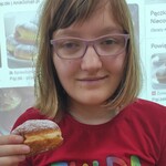 Dziewczyna z pączkiem w ręku.