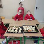 Uczniowie przyglądają się  bułeczkom gotowym do zapiekania.