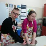 Uczeń trzyma miskę koleżance zagniatającej ciasto.