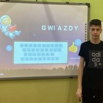 Uczeń stoi obok tablicy interaktywnej.