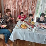 Dwie panie i uczniowie siedzą wokół urodzinowego stołu.