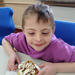 Uczeń trzyma gofra z bitą śmietaną, polewą i owocami.