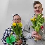 Dwóch chłopaków trzyma bukiety tulipanów.