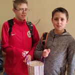 Trzech uczniów i uczennica. Uczniowie stojący w środku trzymają torbę z cukierkami.