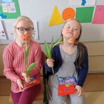 Dziewczynki z tulipanami siedzące na krzesłach.