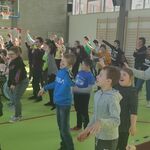 Duża grupa uczniów w trakcie nauki tańca grupowego.