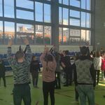 Duża grupa uczniów w trakcie nauki tańca grupowego.