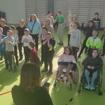 Duża grupa uczniów w trakcie nauki tańca grupowego.