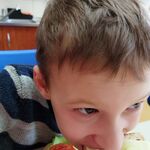 Uczeń gryzie kanapkę z serem, ogórkiem i pomidorem.