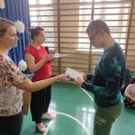 Nauczycielka wręcza dyplom uczniowi.