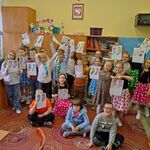 Grupa dzieci z kartkami, na których narysowane są skarpetki.