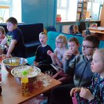 Uczestnicy seansu filmowego, którzy siedzą na krzesłach i kanapie i oglądają film. Przed uczniami stoi stół, a na nim znajdują się przekąski (popcorn, ciastka, chrupki) oraz picie