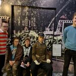 Dwie uczennice siedzą na ławce a dwóch uczniów stoją po obu stronach.