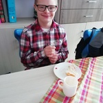 Uczeń siedzi za stołem. Przednim stoi talerz,