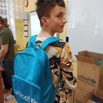 Uczeń w plecaku z UNICEF-u na plecach.