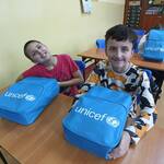 Uczniowie siedzą w ławkach. Przed nimi leżą plecaki z UNICEF-u.