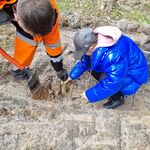 Leśnik zakopuje łopatą dołek, w który uczennica sadzi drzewko