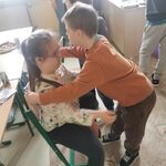 Chłopiec składa życzenia dziewczynce siedzącej na krzesełku.