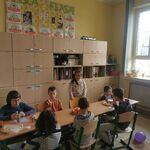 Grupa dzieci wokół urodzinowego stołu.