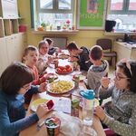 Uczniowie siedzą wokół urodzinowego stołu Mileny.