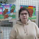 Uczennica na tle wystawy prac plastycznych.