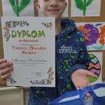 Uczeń prezentuje dyplom otrzymany za udział w konkursie plastycznym.