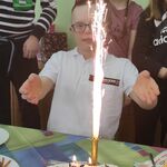 Jubilat i jego urodzinowy tort. Z tyłu uczniowie z klasy.