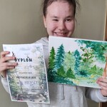 Uczennica prezentuje obraz otrzymany w nagrodę oraz pamiątkowy dyplom za udział w konkursie plastycznym o lesie.