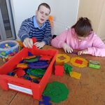 Uczniowie układają wzory z dużych kolorowych klocków w kształcie figur geometrycznych.