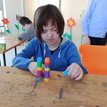 Uczennica układa dwie równe wieże z kolorowych klocków.