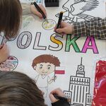 Uczniowie kolorują mazakami plakat.