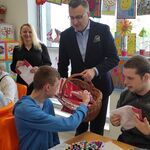 Wiceprezydent Rafał Rudnicki rozdaje uczniom flagi.