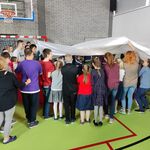Uczniowie trzymają flagę na głowami.