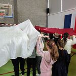 Uczniowie trzymają nad głowami flagę Polski.