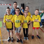 Nauczycielka stoi z grupą uczniów w strojach sportowych